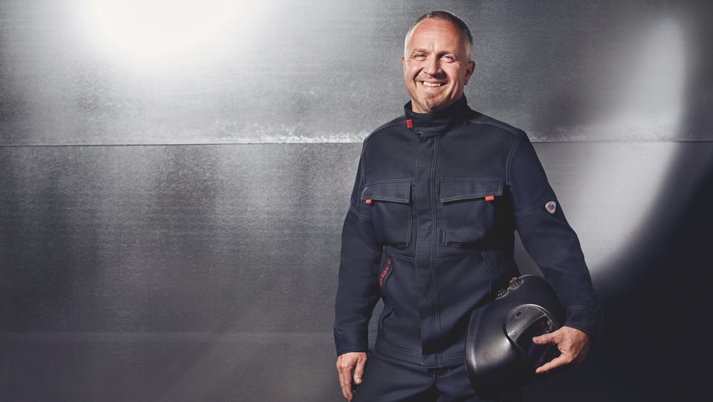 Un homme sourit en portant des vêtements de protection pour soudeurs.