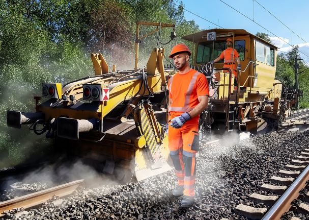 Bahn-Mitarbeiter in Wanrschutzkleidung warten Bahnstrecke.