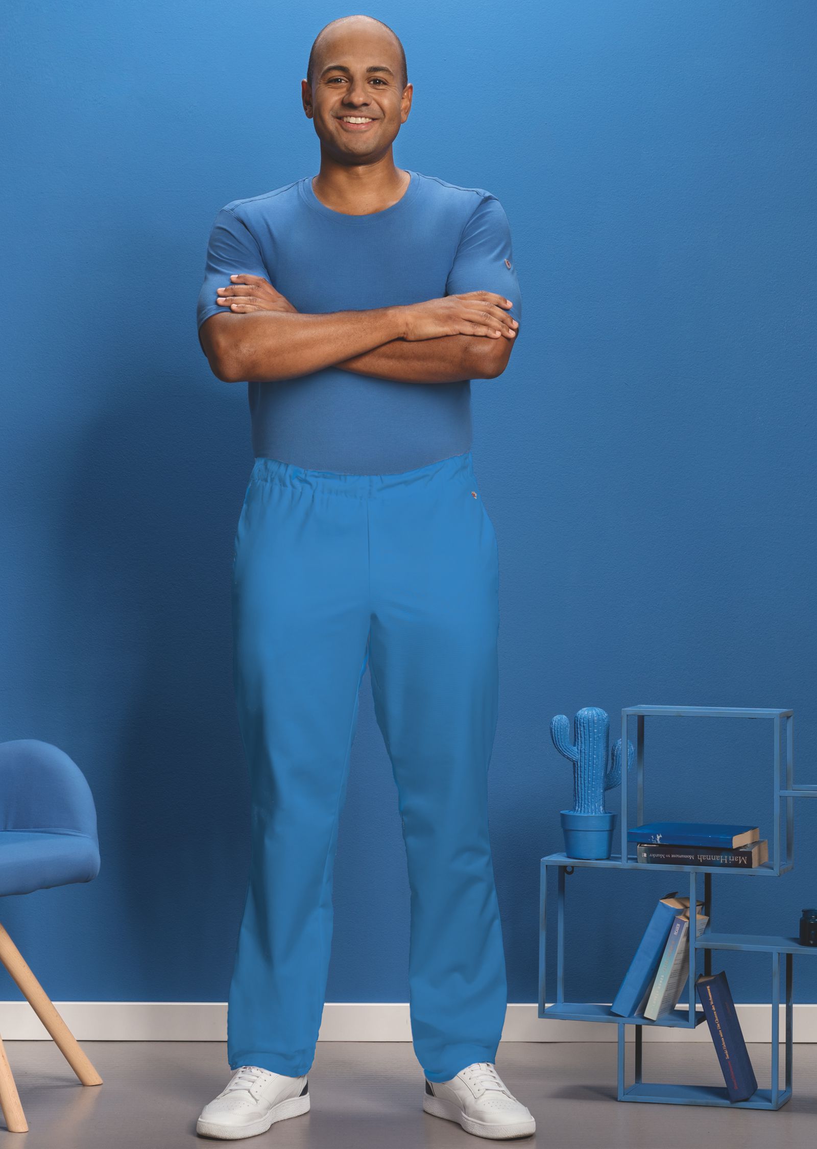 Ein Pfleger trägt eine Pflegeuniform in azurblau.