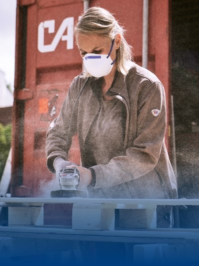 A carpenter wears brown work clothes and processes wood.