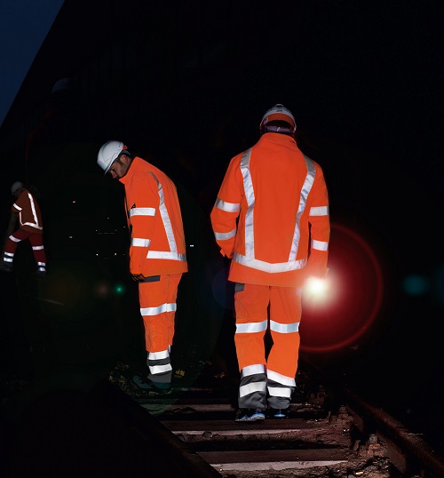 Drei Männer arbeiten in Dunkelheit auf einem Gleis mit High-Vis Warnschutzkleidung .