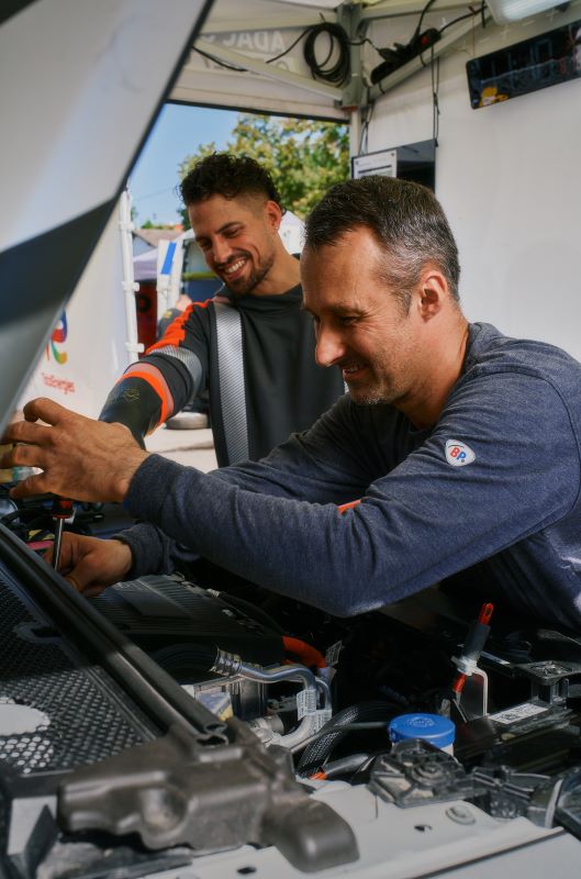 Zwei KFZ Mechaniker warten E-Autos in BP® Arbeitskleidung.