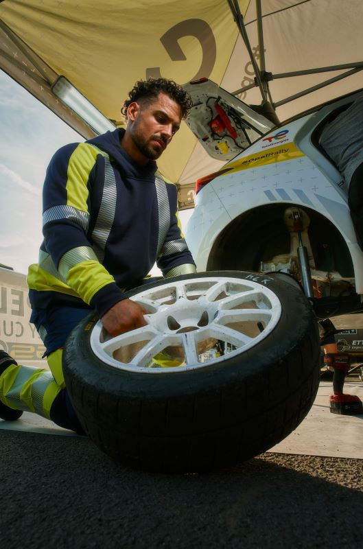 Ein Mann hebt einen Autoreifen in BP® Arbeitskleidung.