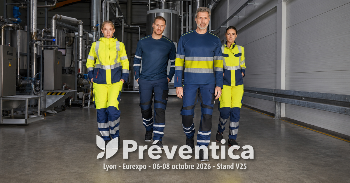 Deux hommes et deux femmes portant des vêtements haute visibilité multinormes dans un hall industriel.