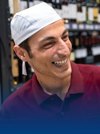 Mitarbeiter in der Gastronomie trägt ein Poloshirt und eine Kopfbinde.