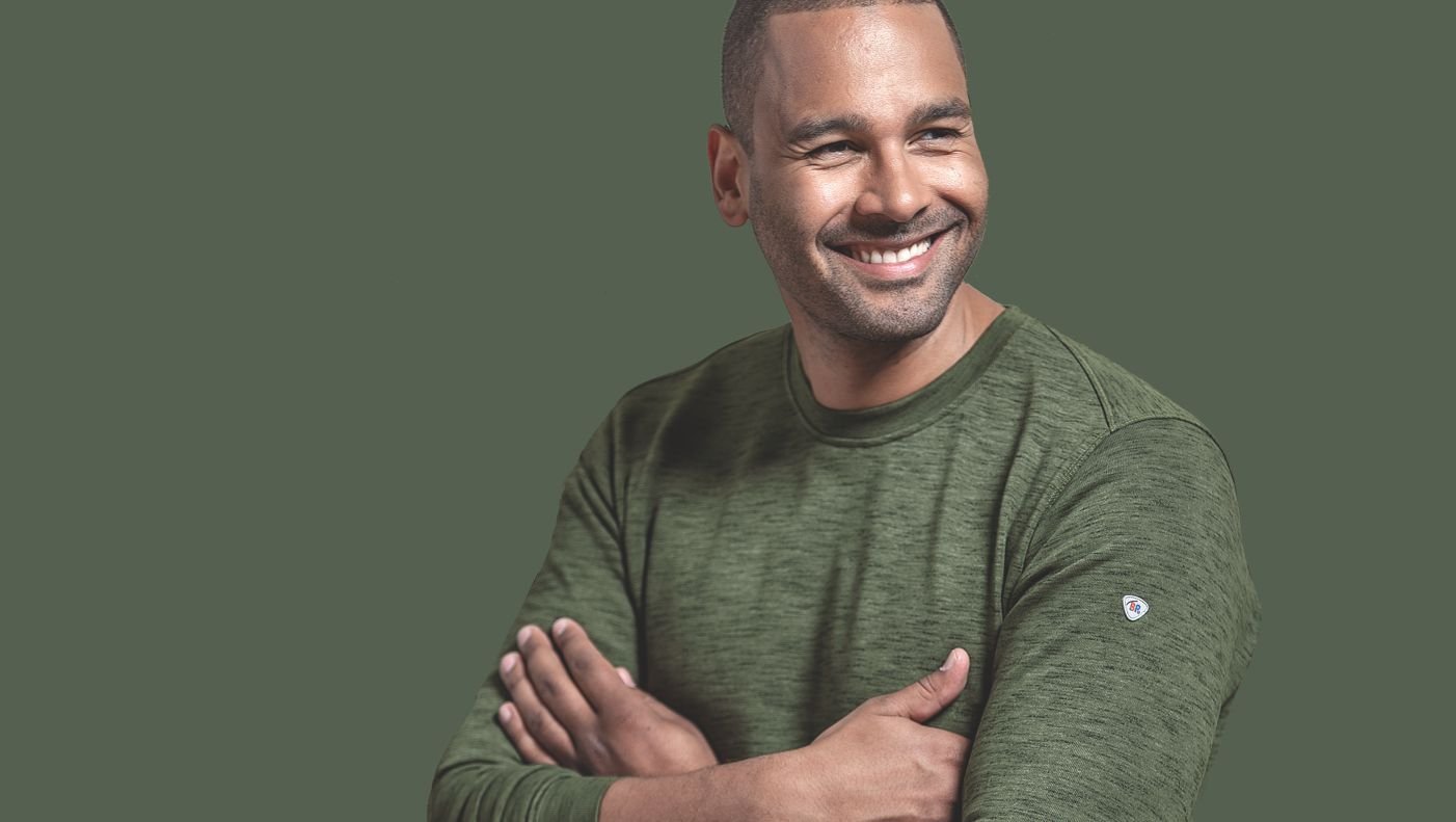 Mann im grünen BP® Sweatshirt mit einem breiten lächeln.