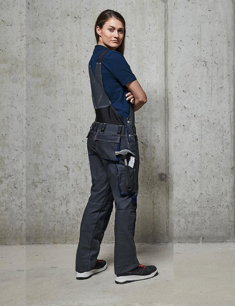 A woman wearing BP® dungarees for women post sideways in front of the camera.