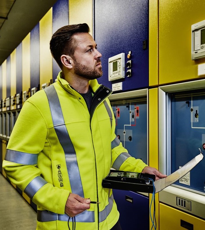 Elektriker in Warnschutz-Fleecejacke  arbeitet an einem Schaltschrank.