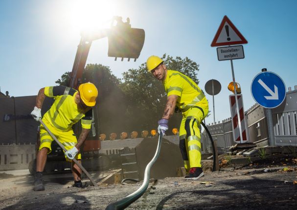 Deux ouvriers du bâtiment travaillant dans la construction de routes portent des vêtements de travail avec protection UV lorsqu'il fait chaud.