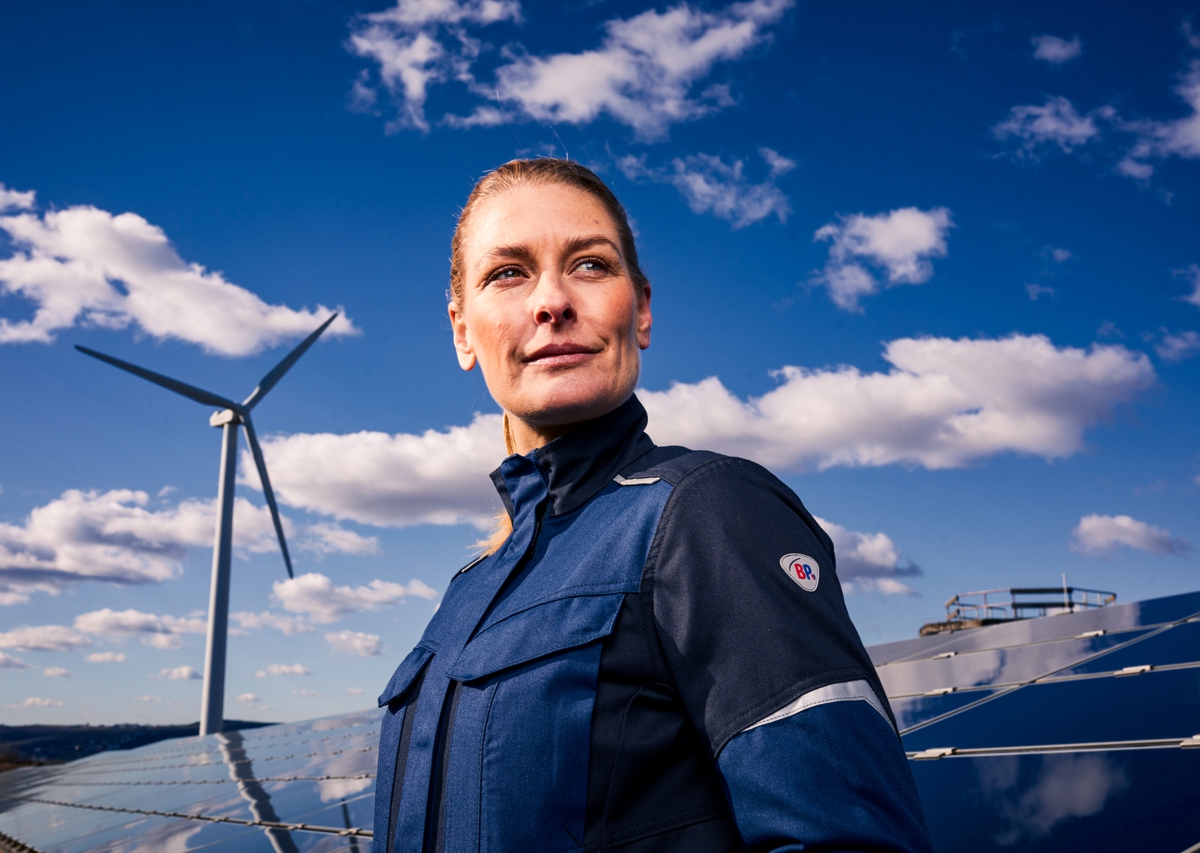 Woman wearing BP® lightweight multinorm jacket APC1 in front of a wind turbine