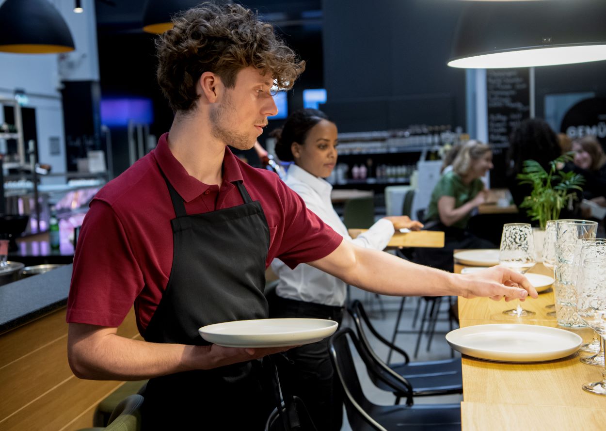 Een man in een schort en een vrouw in een wit shirt serveren in de bistro.