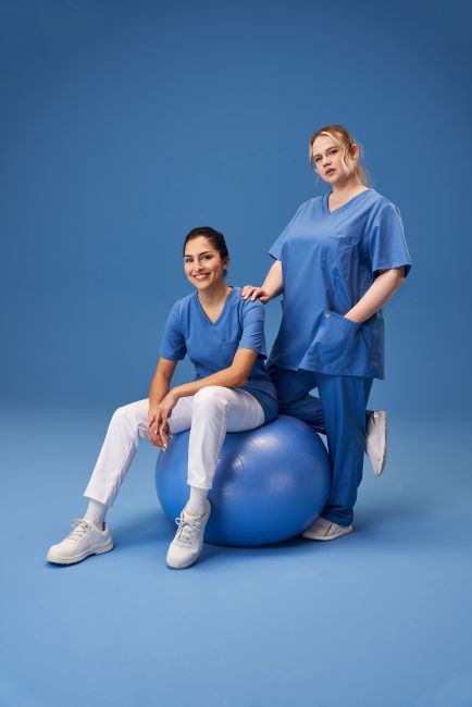 Zwei Pflegerinnen auf Pezzi-Ball in hellblau-weißen Uniformen.