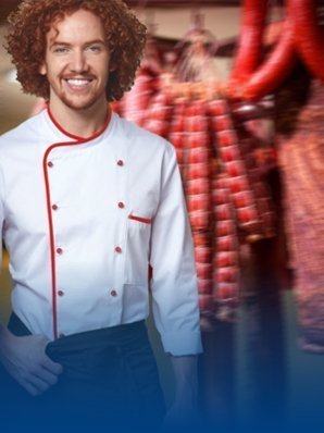 Metzger trägt eine Metzgerjacke. Im Hintergrund sind Fleischprodukte zu sehen.
