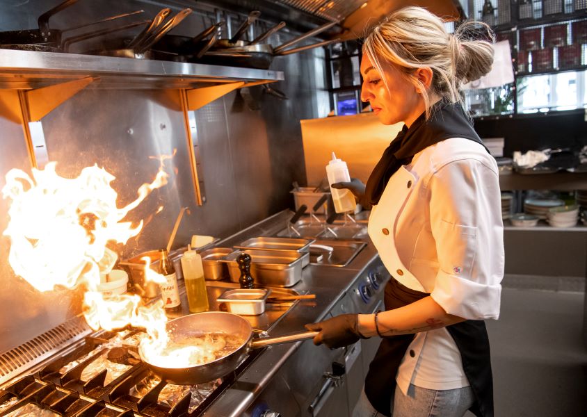 Köchin trägt eine Kochschürze für Damen und kocht in der Küche.