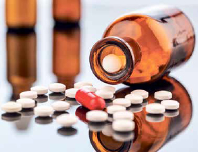 Een blikje met medicijnen ligt open op tafel en er liggen tabletten op tafel.