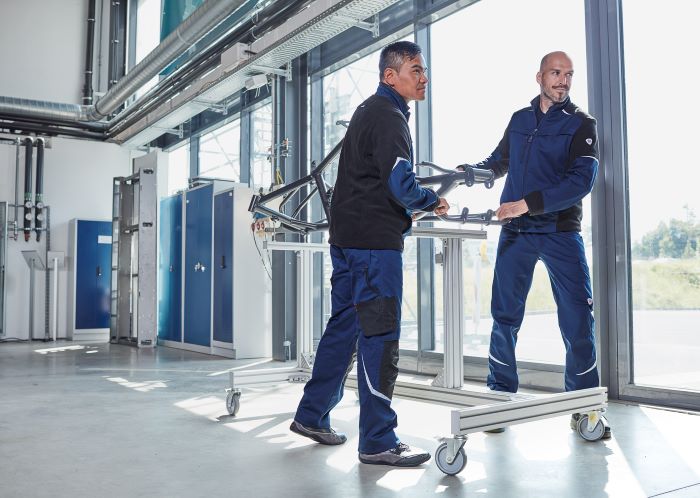 Zwei Arbeiter in blauer Arbeitskleidung arbeiten an Vorrichtung.