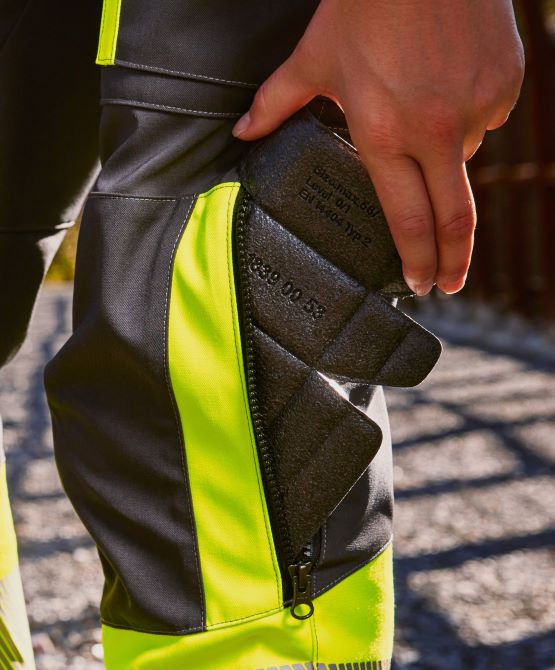 One person places a knee pad in the knee pad pocket of the work trousers.