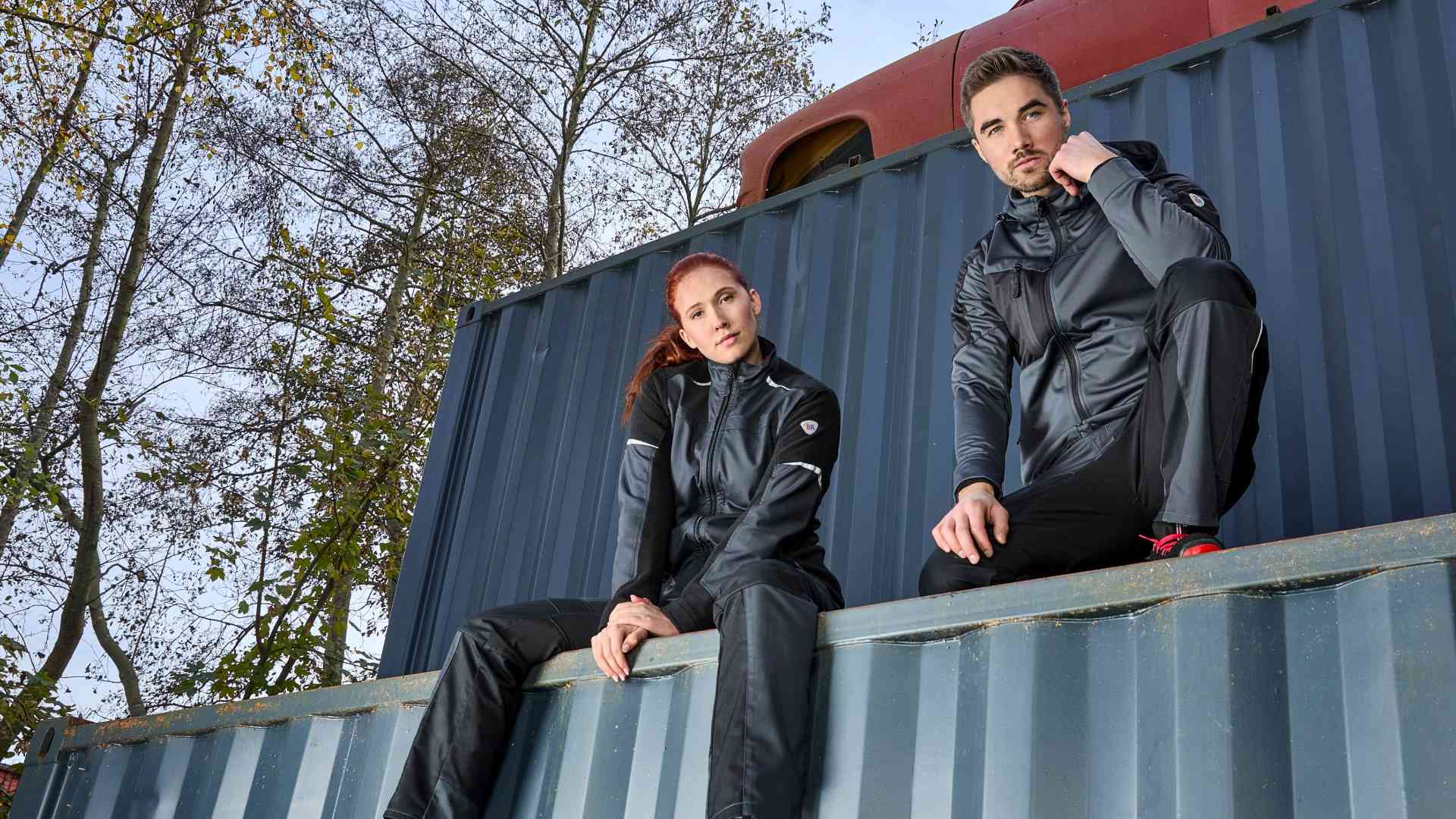 Une femme et un homme sont assis sur un conteneur de vêtements de travail BP®.
